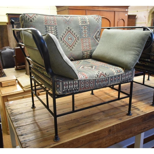 1146 - A pair of wrought iron armchairs, having loose cushions with geometric upholstery, reportedly commis... 