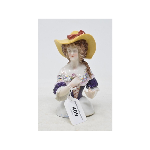 409 - A porcelain half doll, lady with long brown curly hair, yellow hat and a purple dress, holding a pin... 