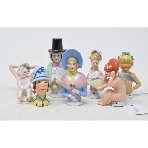 541 - A porcelain half doll, a cherub wearing a red hat, 8 cm high, and seven others (8)