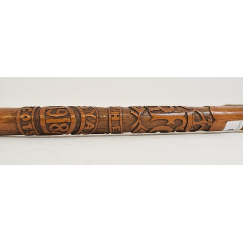 650 - A military themed walking cane, having an L shaped antler handle, the shaft with carved decoration o... 