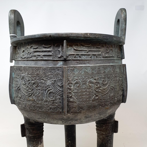 284 - A Chinese bronze censer, with twin handles, decorated clouds and other motifs, on three legs, 27 cm ... 