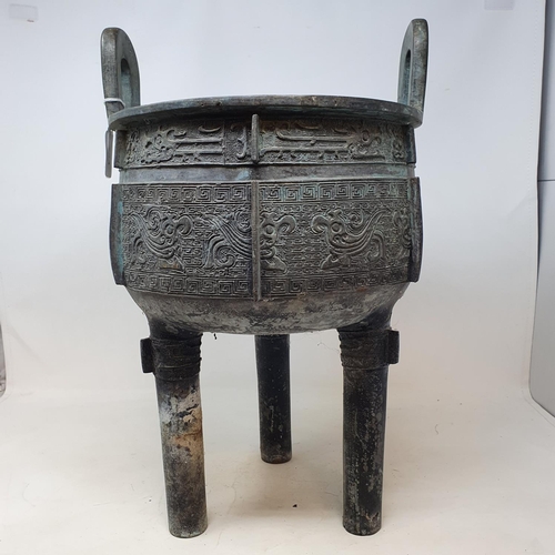 284 - A Chinese bronze censer, with twin handles, decorated clouds and other motifs, on three legs, 27 cm ... 