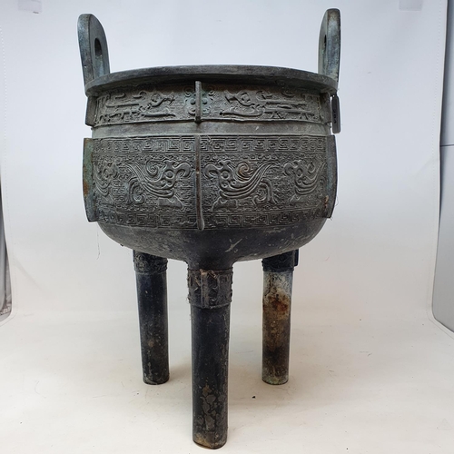 284 - A Chinese bronze censer, with twin handles, decorated clouds and other motifs, on three legs, 27 cm ... 