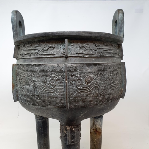 284 - A Chinese bronze censer, with twin handles, decorated clouds and other motifs, on three legs, 27 cm ... 
