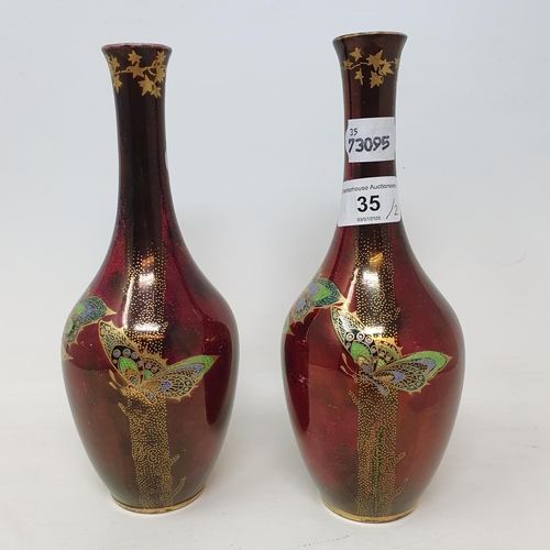 35 - A pair of Devon Fieldings Sylvan Lustrine bottle vases decorated with butterflies on a deep red lust... 