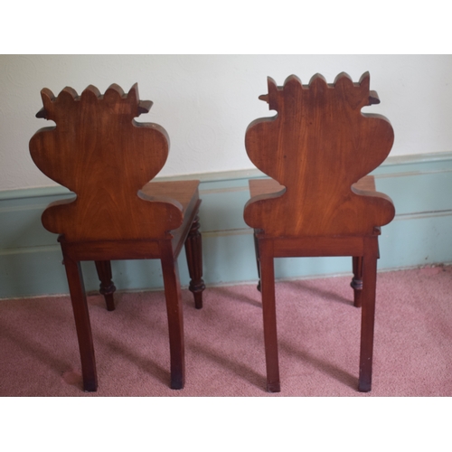 14 - A pair of late Regency mahogany hall chairs, with cartouche shaped backs and tapering reeded front l... 