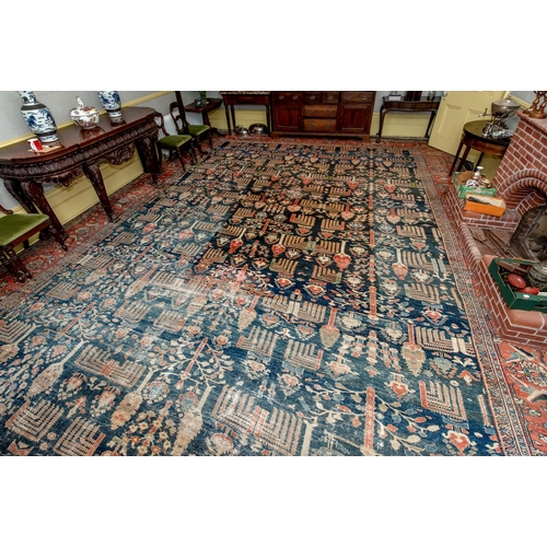 174 - A large carpet, with floral and geometric motifs on a blue ground, within a multi border, worn, fade... 