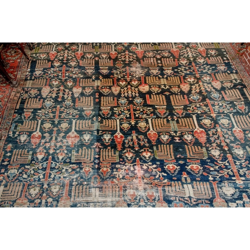 174 - A large carpet, with floral and geometric motifs on a blue ground, within a multi border, worn, fade... 