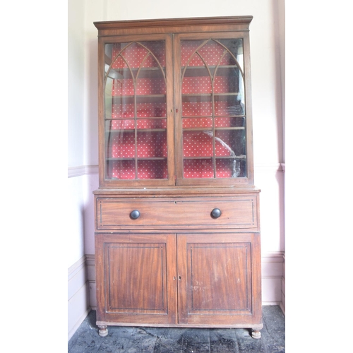 232 - A mahogany bookcase on chest, having a pair of lancet bar glazed doors above a secretaire drawer, wi... 