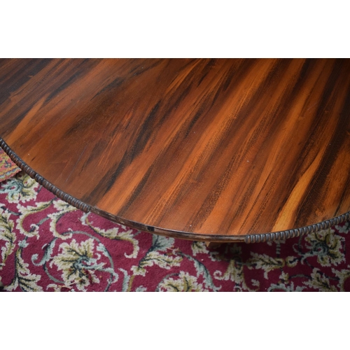 107 - An early Victorian rosewood centre table, the tilt top on an octagonal column and concave sided plat... 