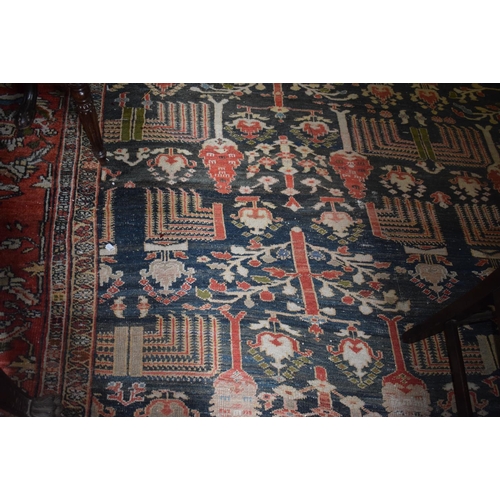 174 - A large carpet, with floral and geometric motifs on a blue ground, within a multi border, worn, fade... 