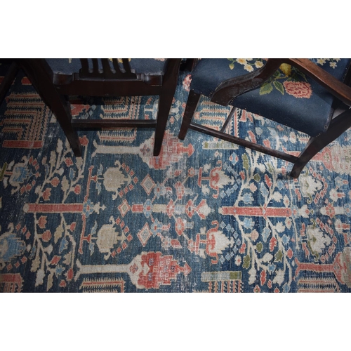 174 - A large carpet, with floral and geometric motifs on a blue ground, within a multi border, worn, fade... 