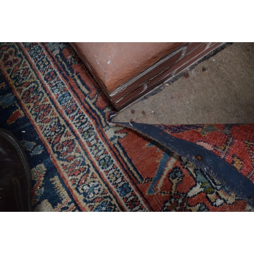 174 - A large carpet, with floral and geometric motifs on a blue ground, within a multi border, worn, fade... 