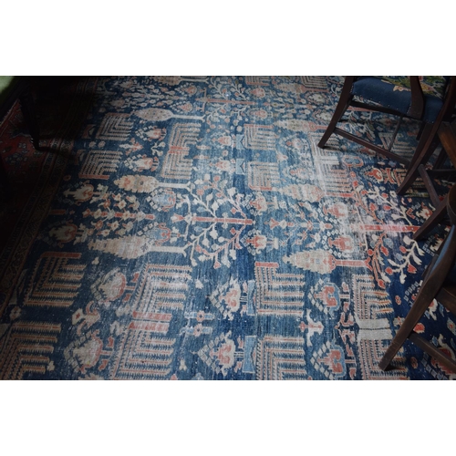 174 - A large carpet, with floral and geometric motifs on a blue ground, within a multi border, worn, fade... 