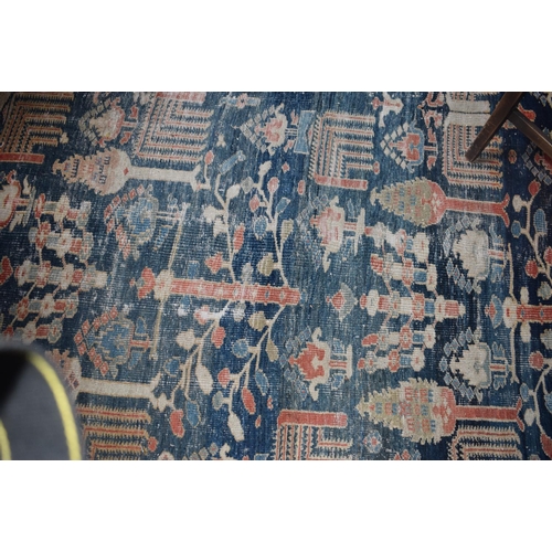 174 - A large carpet, with floral and geometric motifs on a blue ground, within a multi border, worn, fade... 