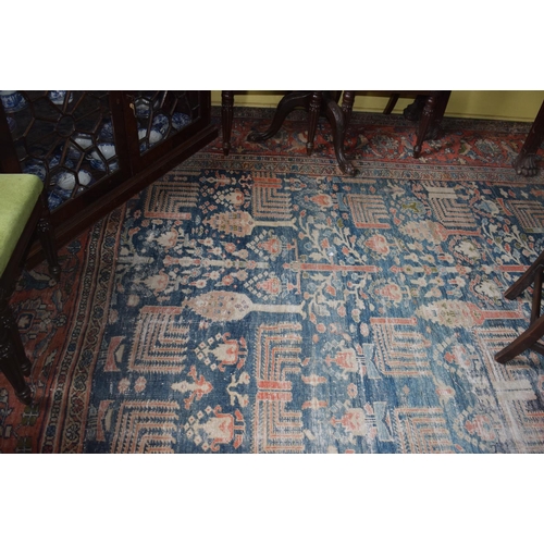 174 - A large carpet, with floral and geometric motifs on a blue ground, within a multi border, worn, fade... 