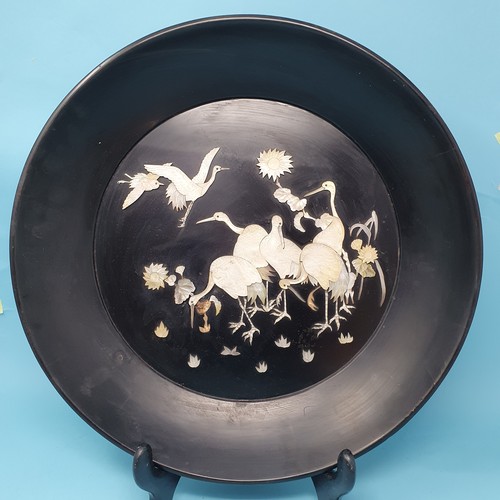 306 - An early 20th century Japanese black lacquered plaque, decorated cranes and flowers, 40 cm diameter