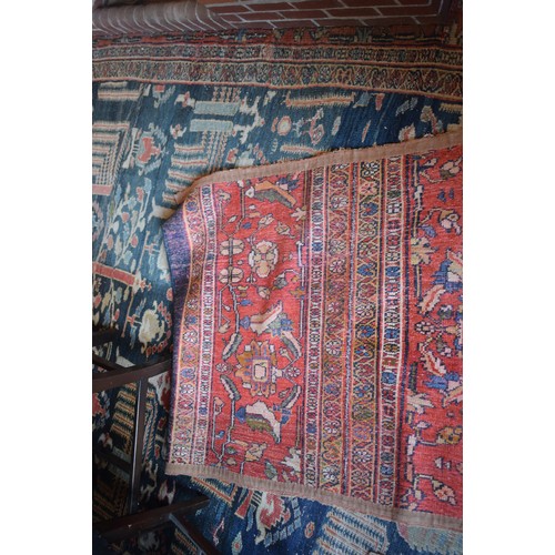 174 - A large carpet, with floral and geometric motifs on a blue ground, within a multi border, worn, fade... 