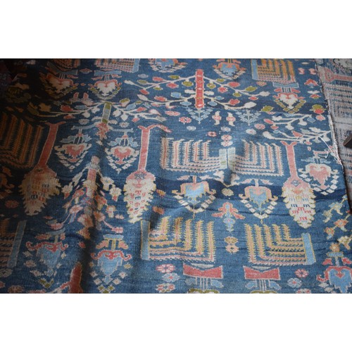 174 - A large carpet, with floral and geometric motifs on a blue ground, within a multi border, worn, fade... 