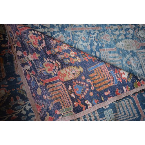 174 - A large carpet, with floral and geometric motifs on a blue ground, within a multi border, worn, fade... 