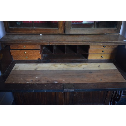 232 - A mahogany bookcase on chest, having a pair of lancet bar glazed doors above a secretaire drawer, wi... 