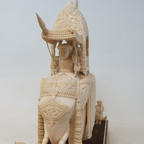 295 - A late 19th century carved ivory elephant, carrying a howdah, carrying two figures escorted by four ... 