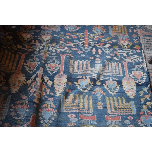 174 - A large carpet, with floral and geometric motifs on a blue ground, within a multi border, worn, fade... 