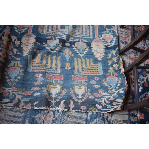 174 - A large carpet, with floral and geometric motifs on a blue ground, within a multi border, worn, fade... 