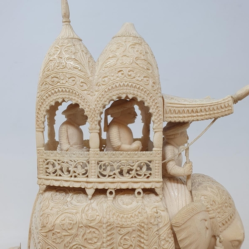 295 - A late 19th century carved ivory elephant, carrying a howdah, carrying two figures escorted by four ... 