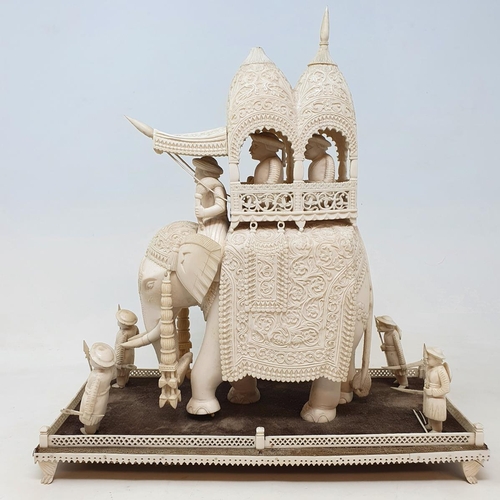 295 - A late 19th century carved ivory elephant, carrying a howdah, carrying two figures escorted by four ... 