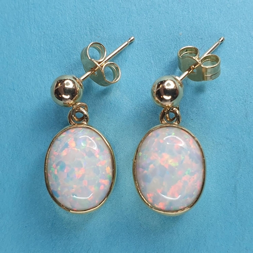 233 - A modern pair of of yellow metal and opal drop earrings