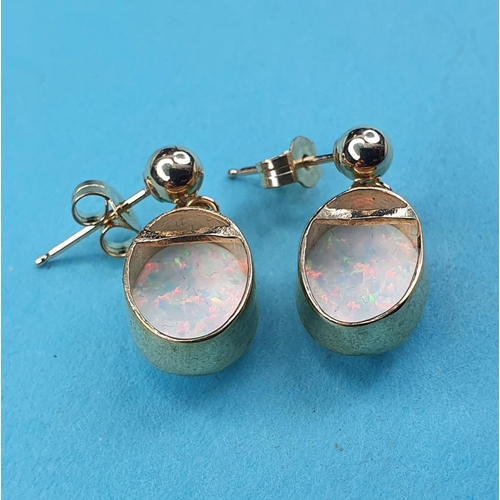 233 - A modern pair of of yellow metal and opal drop earrings