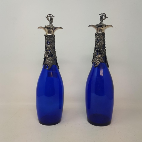 643 - A pair of modern blue glass and decanters, with grape and vine plated mounts, 34 cm high (2)
