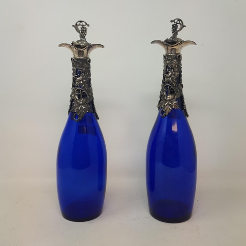 643 - A pair of modern blue glass and decanters, with grape and vine plated mounts, 34 cm high (2)