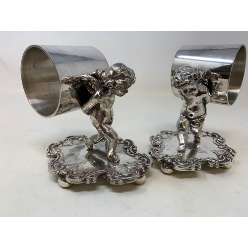 10 - A set of ten silver plated napkin rings held by cherubs, on shaped bases, 10 cm high (10)