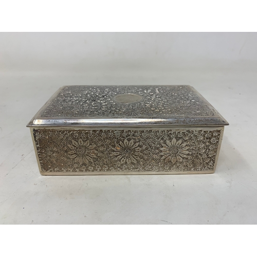 28 - A Persian silver coloured metal table cigarette box, decorated flowers and foliage, 13.5 cm wide