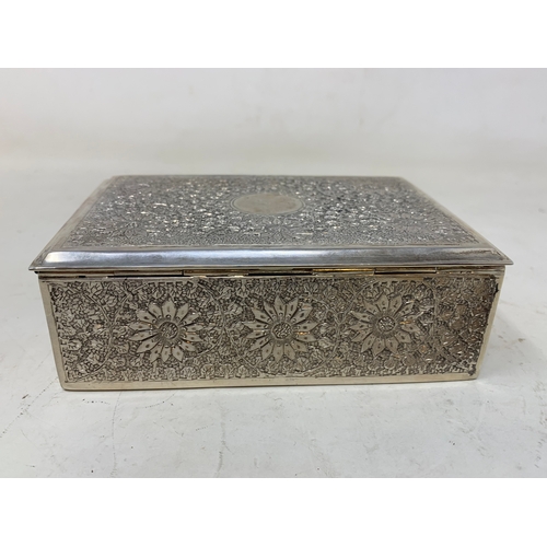 28 - A Persian silver coloured metal table cigarette box, decorated flowers and foliage, 13.5 cm wide