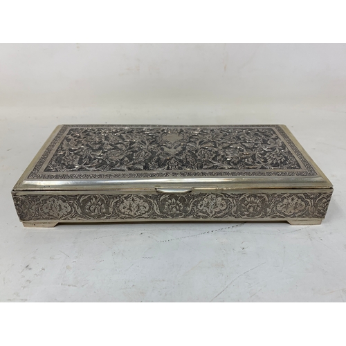 29 - A Persian silver coloured metal table cigarette box, decorated birds, flowers and foliage, 16 cm wid... 