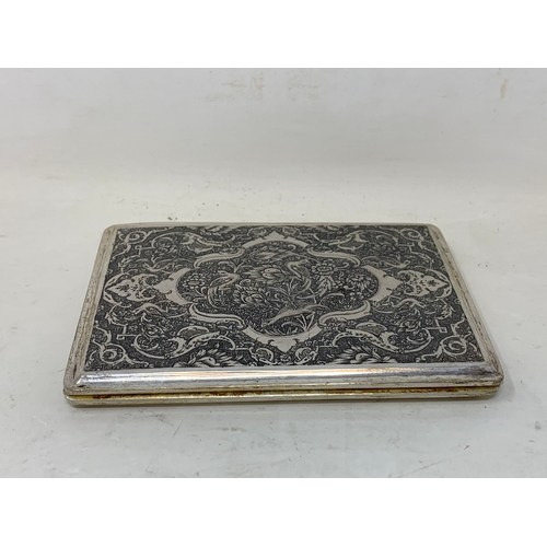 32 - A Persian silver coloured metal cigarette case, decorated birds, flowers and foliage, 10.5 cm wide