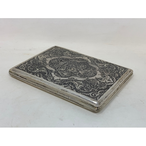 32 - A Persian silver coloured metal cigarette case, decorated birds, flowers and foliage, 10.5 cm wide