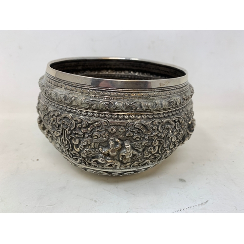 36 - A Burmese style silver coloured metal bowl, embossed figures and foliage, dented and holed, 13 cm di... 