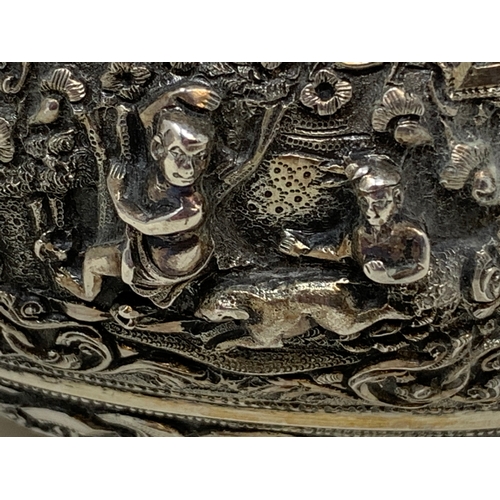 36 - A Burmese style silver coloured metal bowl, embossed figures and foliage, dented and holed, 13 cm di... 