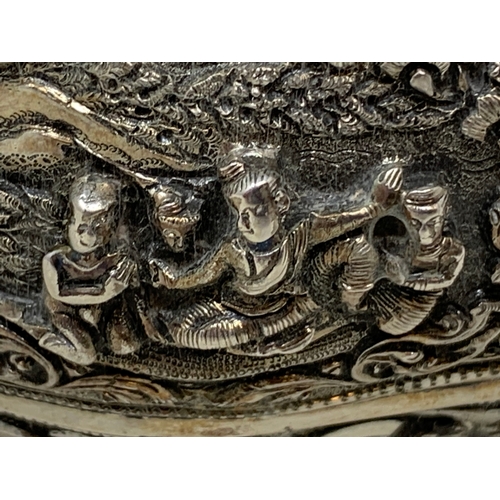 36 - A Burmese style silver coloured metal bowl, embossed figures and foliage, dented and holed, 13 cm di... 