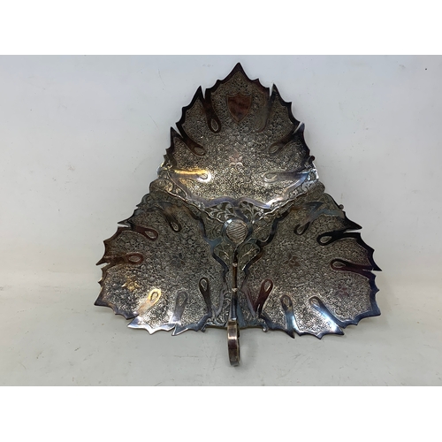 37 - A Malaysian style silver coloured metal leaf shaped dish, 19 cm wide, a similar silver coloured meta... 