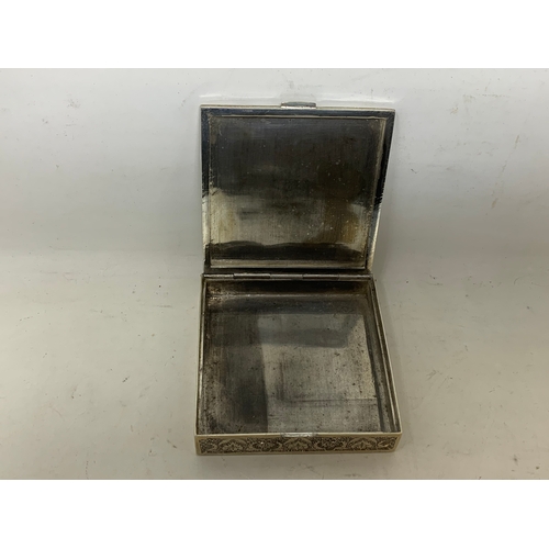 40 - A Persian silver coloured metal cigarette box, decorated a labourer digging, 8.5 cm wide