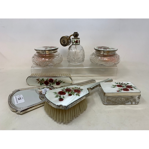 53 - A silver and enamel seven piece dressing table set, decorated roses, Birmingham 1959