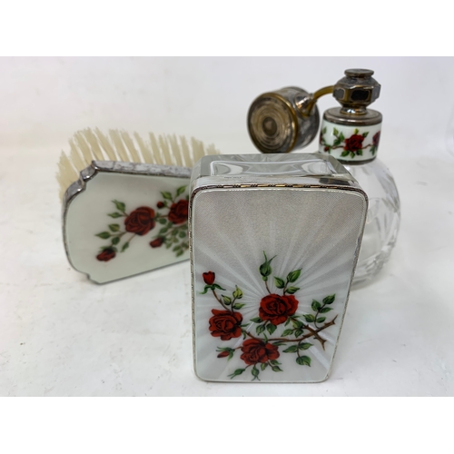 53 - A silver and enamel seven piece dressing table set, decorated roses, Birmingham 1959