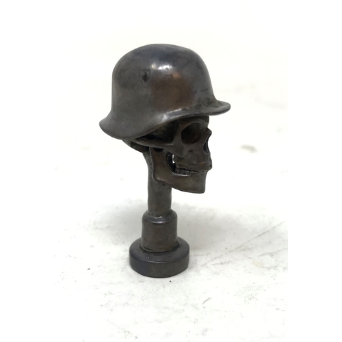 108 - A bronze pipe tamper, in the form of a skull wearing a helmet