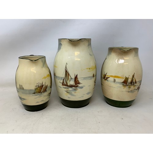 347 - A graduated set of three Royal Doulton jugs, decorated fishing boats, some crazing, the largest 20 c... 