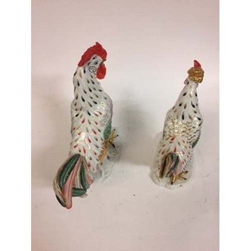 604 - A Continental porcelain model of a cockerel, 28 cm high, and a matching chicken, 22 cm high (2)